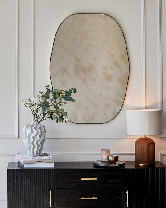 Elegant contemporary black wooden sideboard with vertical ridged front panels and brass handle accents. The piece features a sleek surface ideal for decorative displays, with a modern aesthetic that would complement a variety of interior designs.