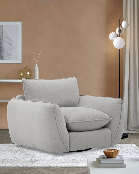 Cozy gray swivel chair with plush cushions, accompanied by a decorative bowl on a white table, next to a modern floor lamp.