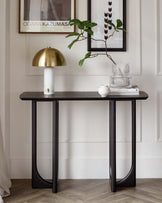 Elegant modern console table with a dark stone or wood top and curved metal legs. The sleek design features a narrow rectangular surface, ideal for hallways or living room accents.