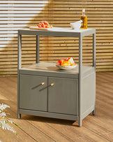 Modern gray storage cart with two shelves, featuring closed cabinets and a wooden top, styled with fresh produce and olive oil.