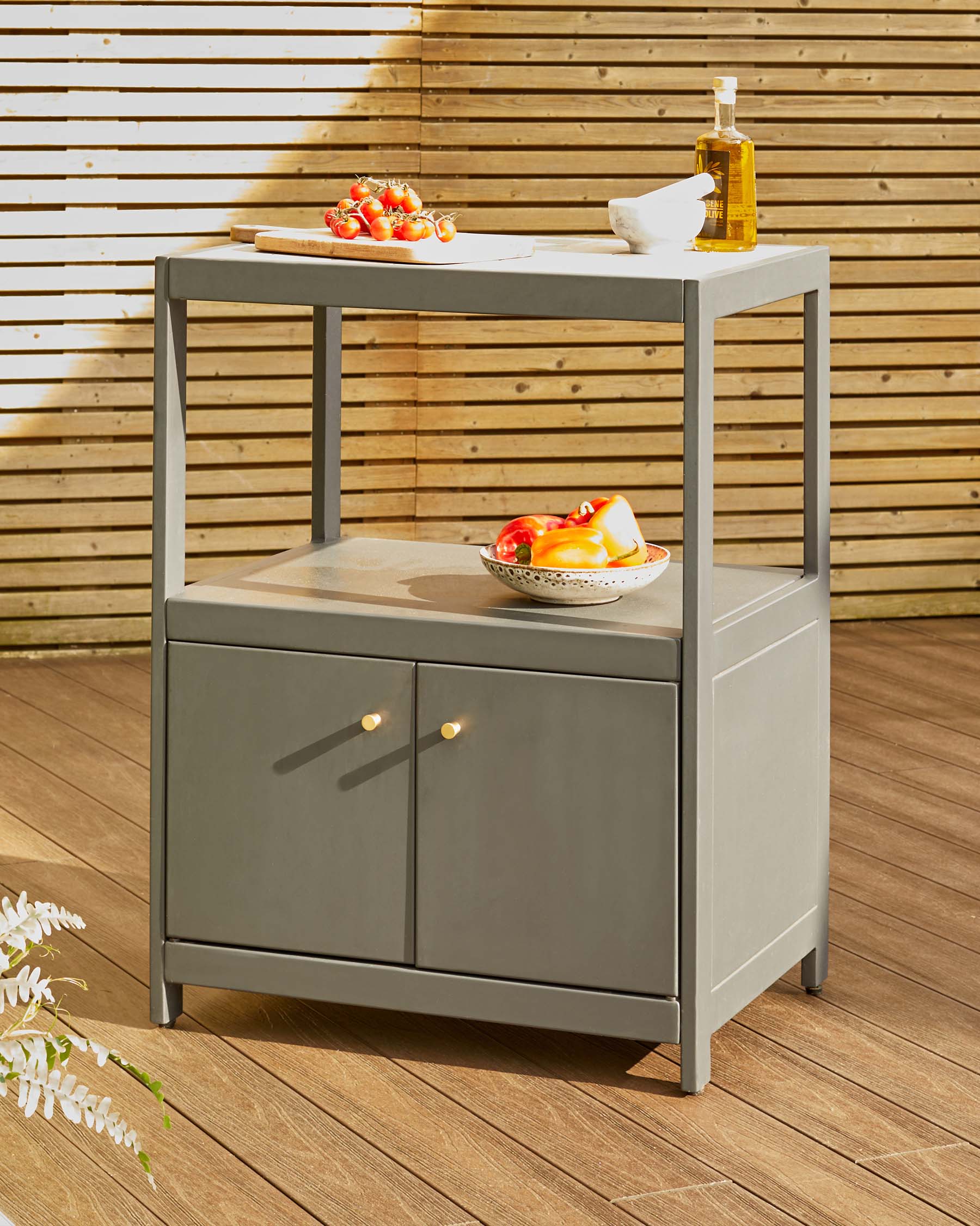 Modern gray storage cart with two shelves, featuring closed cabinets and a wooden top, styled with fresh produce and olive oil.