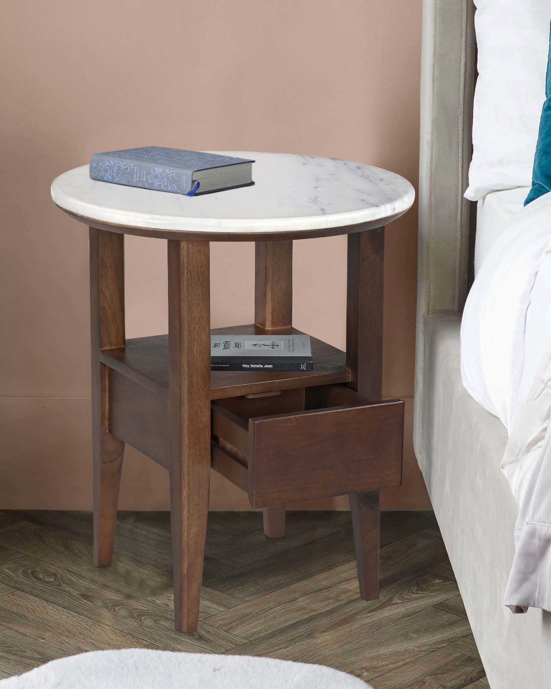 A sleek wooden side table with a round marble top, featuring a lower shelf and a drawer for storage.