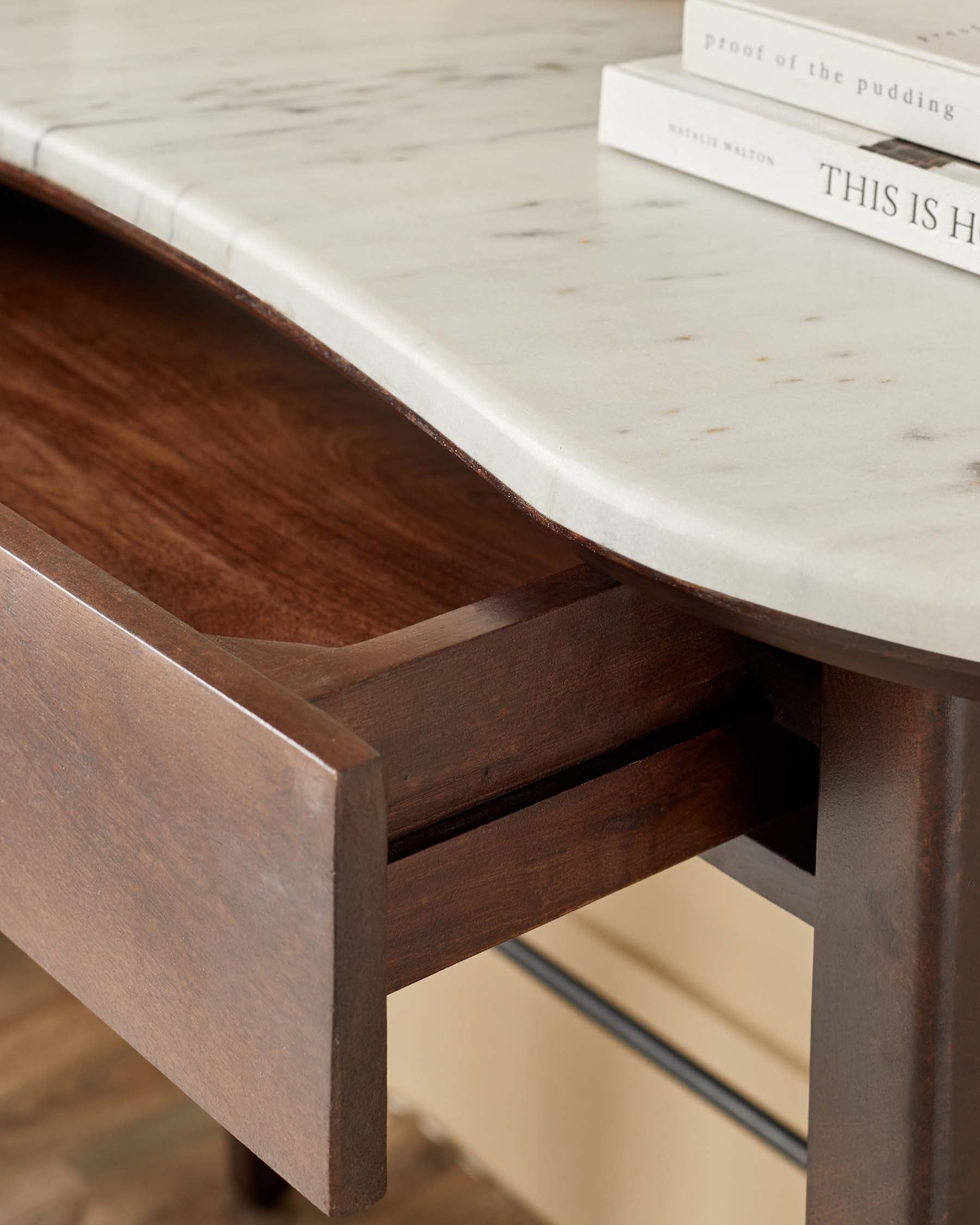 A chic desk features a curved marble top and a warm wood drawer detailing, blending elegance and functionality.