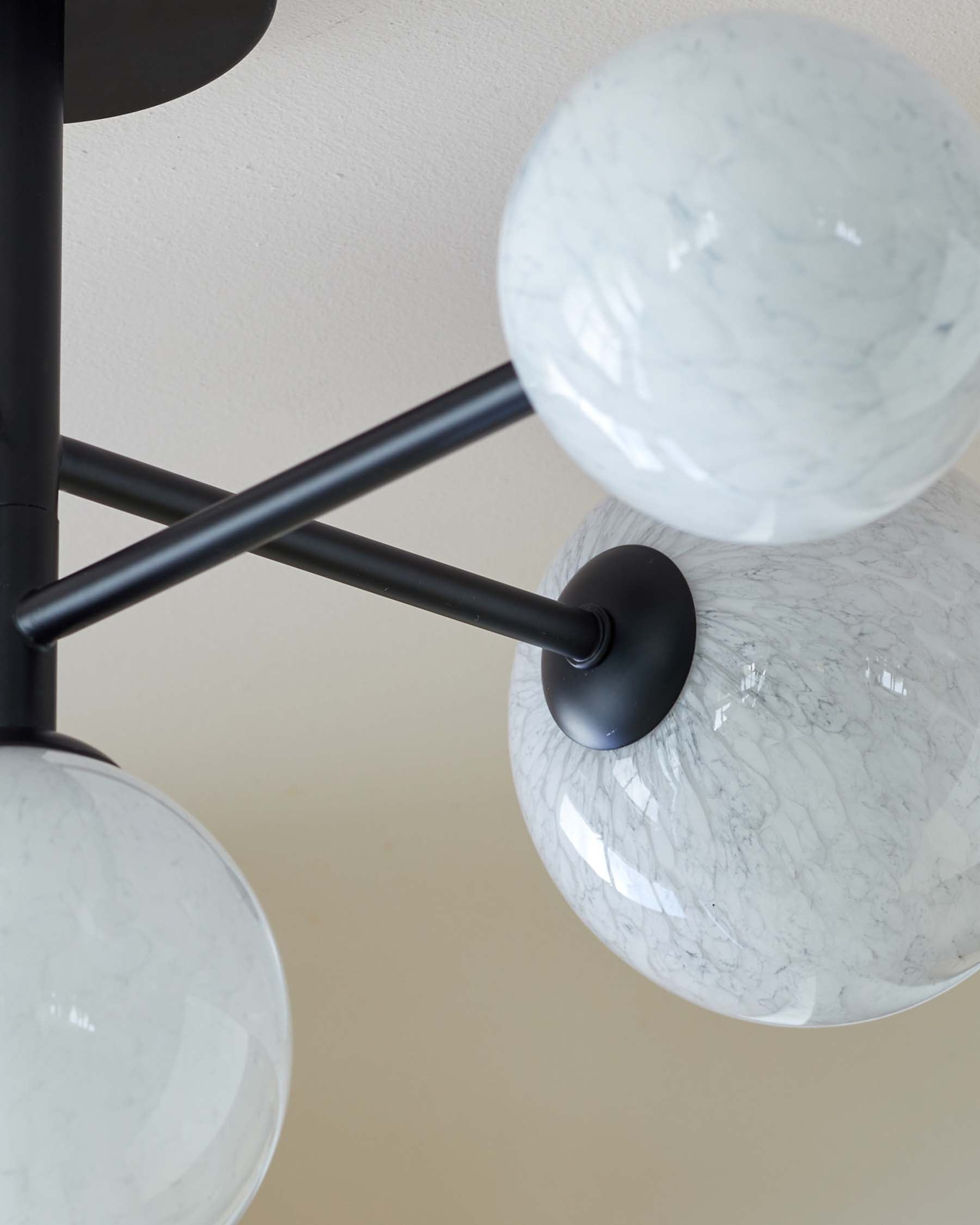 Modern chandelier with marble-patterned glass spheres and matte black metal fixture.