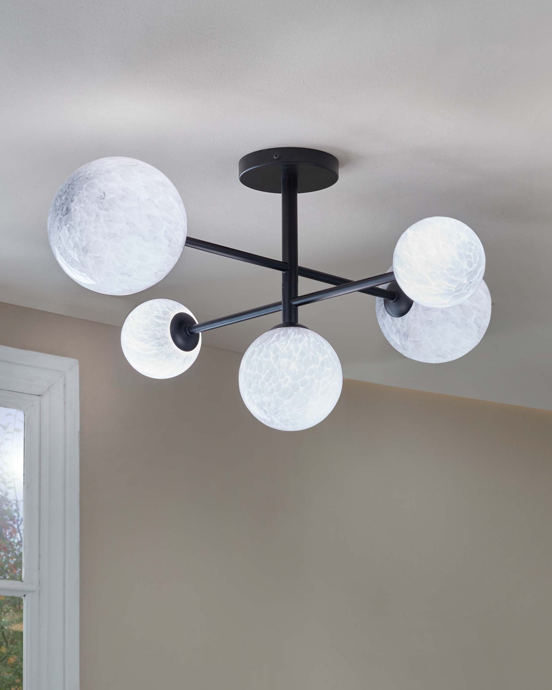 Modern ceiling light fixture with five globe-shaped frosted glass shades mounted on a matte black armature, designed for contemporary interior lighting.