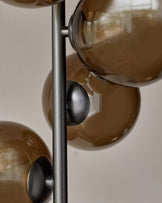 Modern floor lamp featuring a vertical metal pole with multiple round, smoky glass shades attached at different heights.