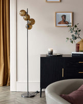 Contemporary black sideboard with vertical grooves and brass hardware, paired with a modern floor lamp featuring a vertical stand and round amber glass shades.