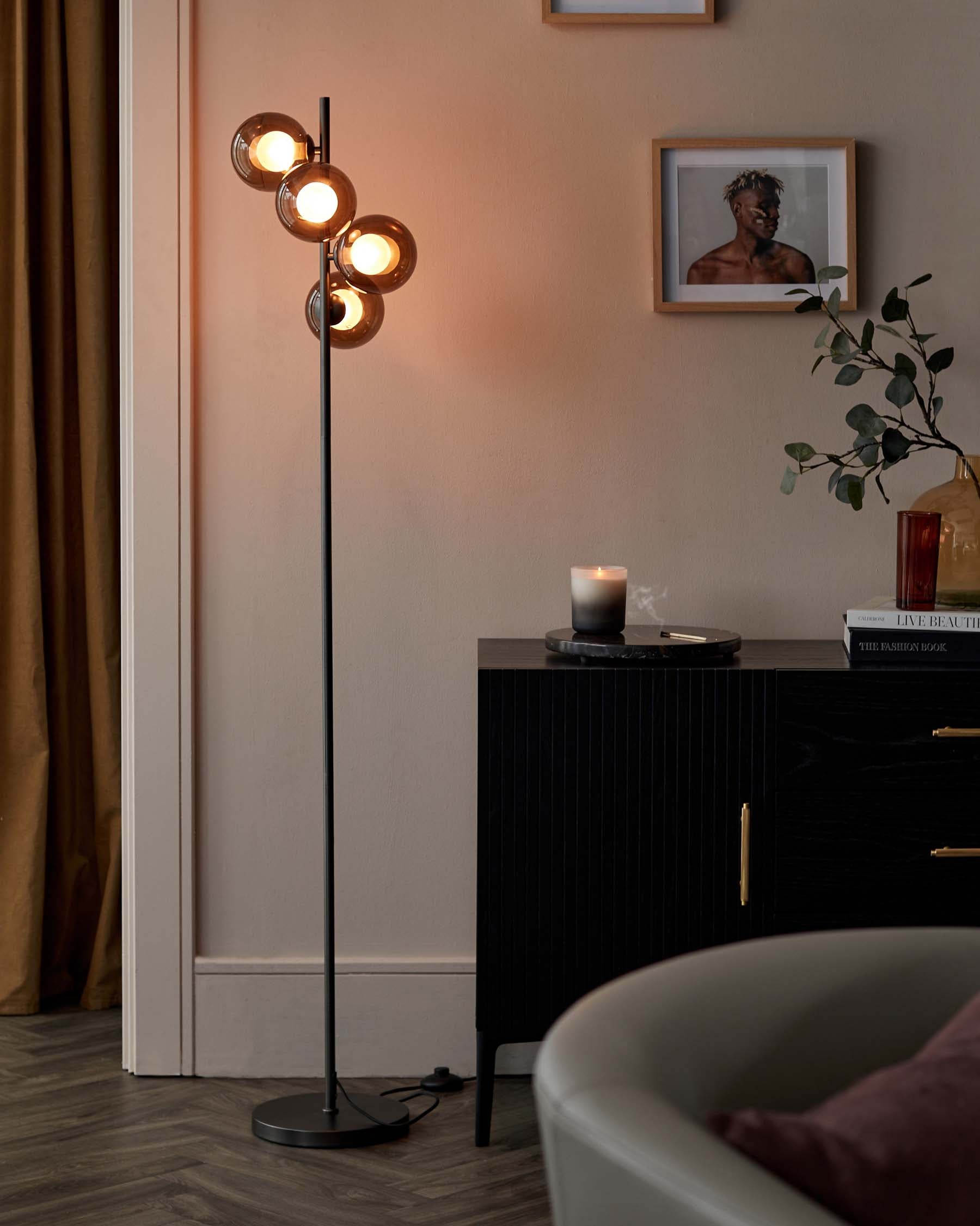 Elegant contemporary floor lamp with a matte black finish and four adjustable spherical shades, paired with a sleek black sideboard featuring vertical ribbed textures and brass handles.