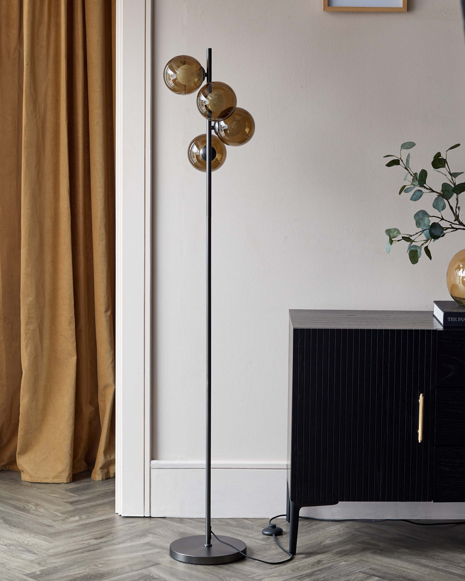 Modern black floor lamp with four globe-shaped amber glass shades positioned at various angles on a central column, paired with a contemporary black ribbed cabinet featuring an elegant brass handle.Please note that while the image includes a floor lamp, which could be considered a lighting fixture rather than furniture, it is described because it complements the furniture item, the cabinet, in the setting.