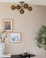 Modern black round side table displaying a decorative vase, books, and a lit candle, complementing an interior space with earth-toned walls and framed artwork.