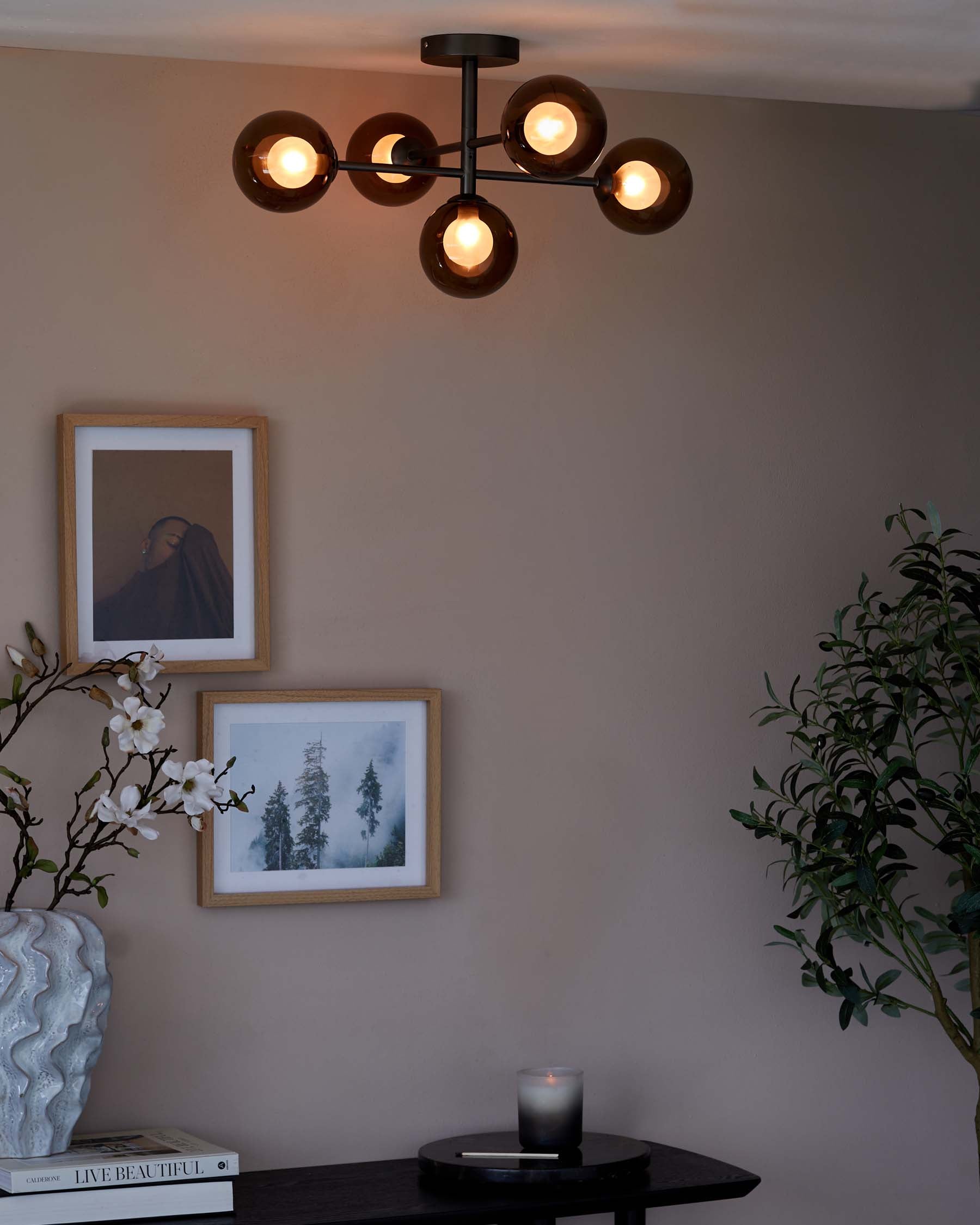 A minimalist and contemporary round black coffee table, featuring a matte finish and a slender yet sturdy profile suitable for a chic living space. The table is adorned with books, a textured vase with white artificial flowers, and a lit candle, adding warmth and elegance to the setting.