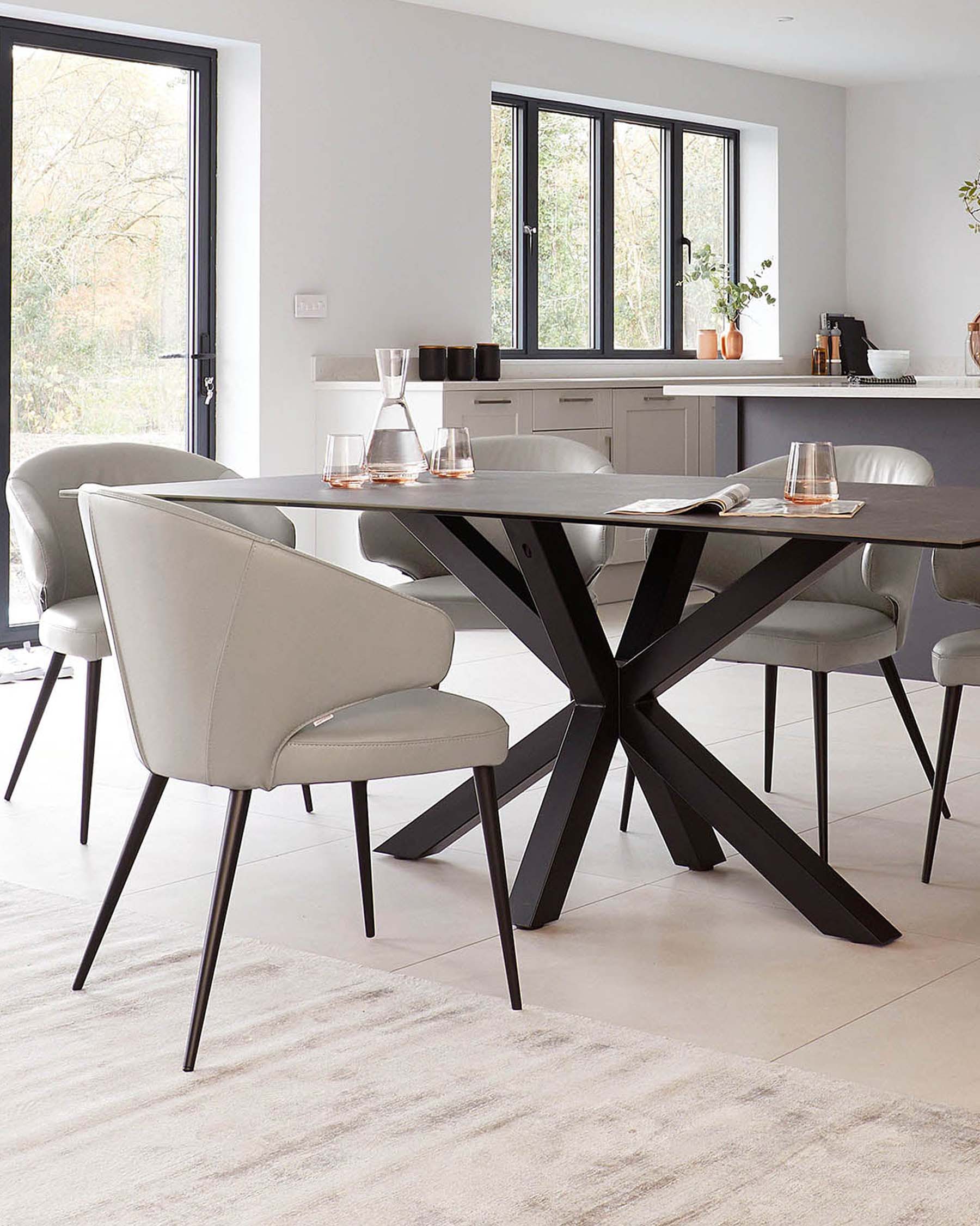 A modern dining table with a black, star-shaped base and light grey chairs featuring sleek design and tapered legs.