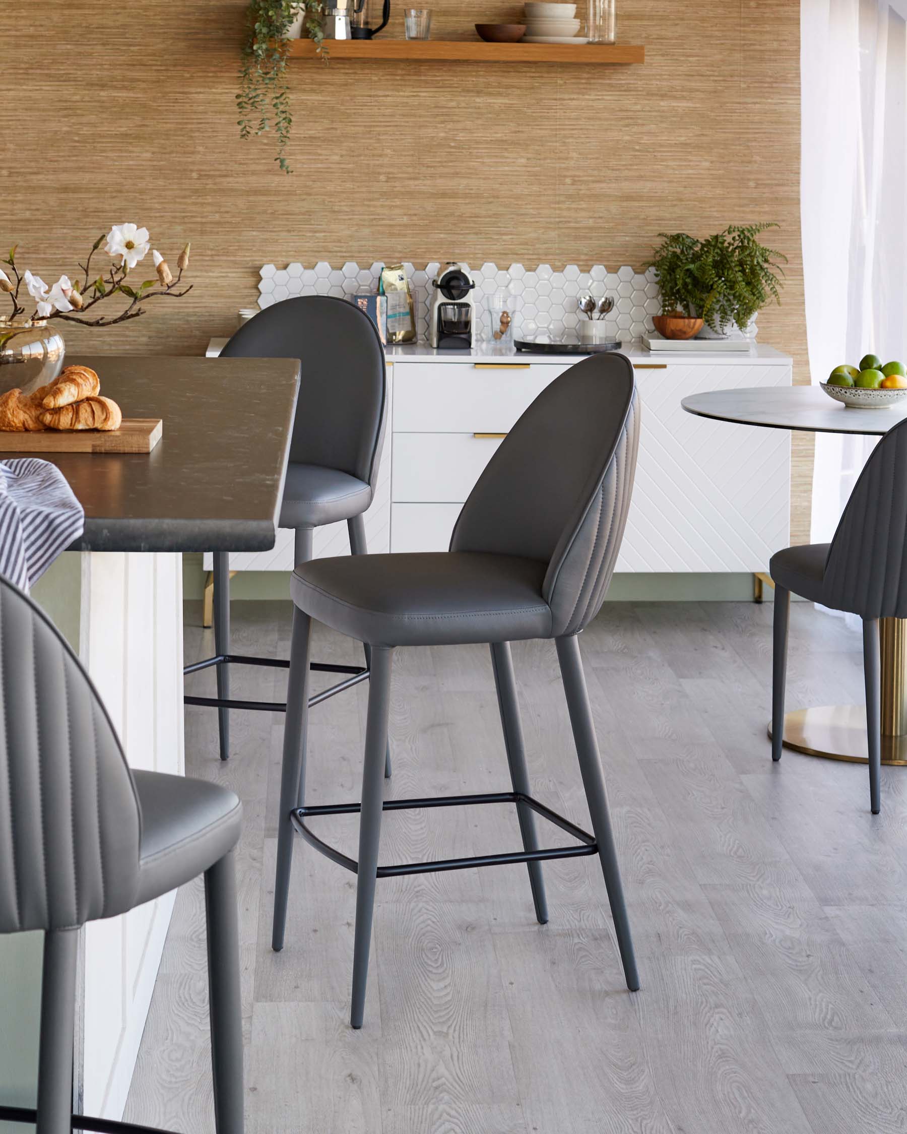 Stylish gray barstools with padded seats and industrial legs at a modern kitchen island, complemented by a round dining table.