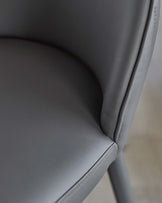 Close-up of a sleek, modern gray chair featuring a curved back and smooth leather upholstery, perfect for contemporary spaces.