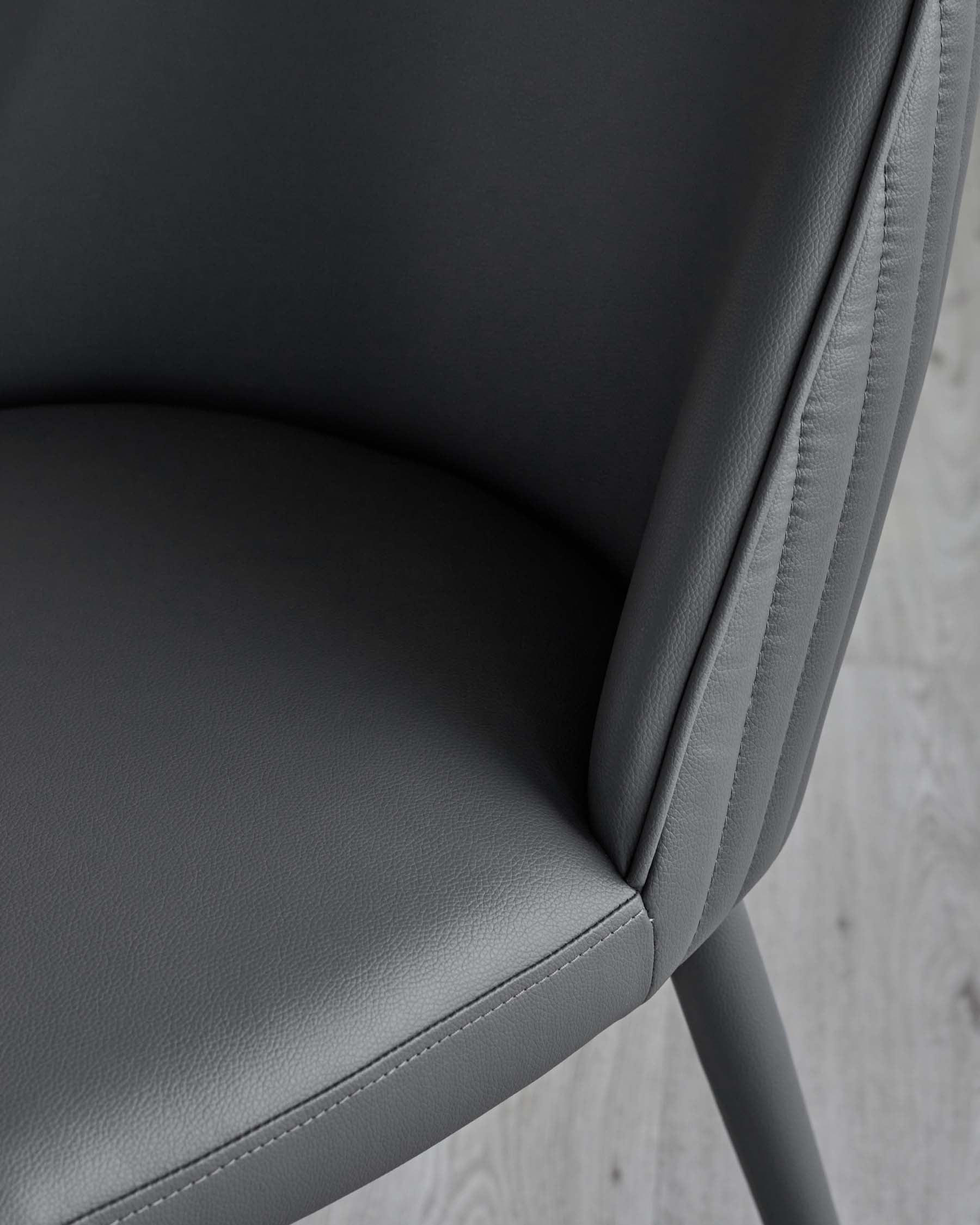 A sleek grey upholstered chair with a curved backrest and minimalist design, featuring subtle stitching details.