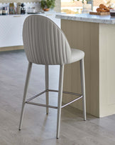 Stylish light grey bar stool with a ribbed backrest and slender metal legs, positioned near a marble-top kitchen island.