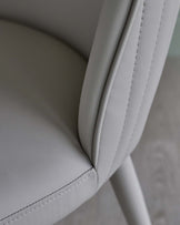 Close-up of a modern, lightly textured grey leather armchair showcasing sleek design and elegant stitching details.