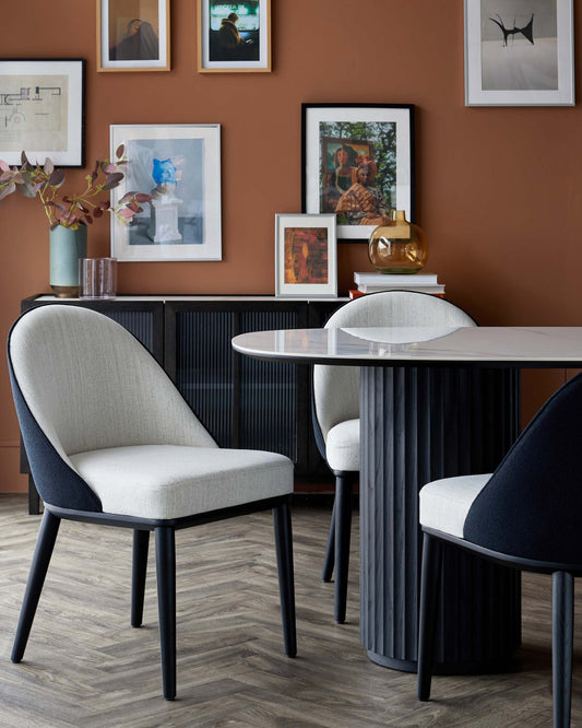 Elegant dining area featuring a modern round table with a textured base and soft, upholstered chairs in neutral tones.