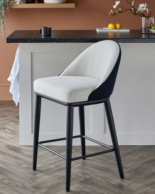 Sleek bar stool with a cushioned seat in light fabric and contrasting dark backrest, supported by a sturdy black frame.