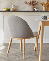 A modern gray upholstered chair with curved backrest and light wooden legs, paired with a sleek, minimalist table.