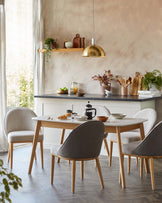 A modern dining set featuring a white tabletop, wooden legs, and upholstered chairs in light grey and dark grey fabrics.