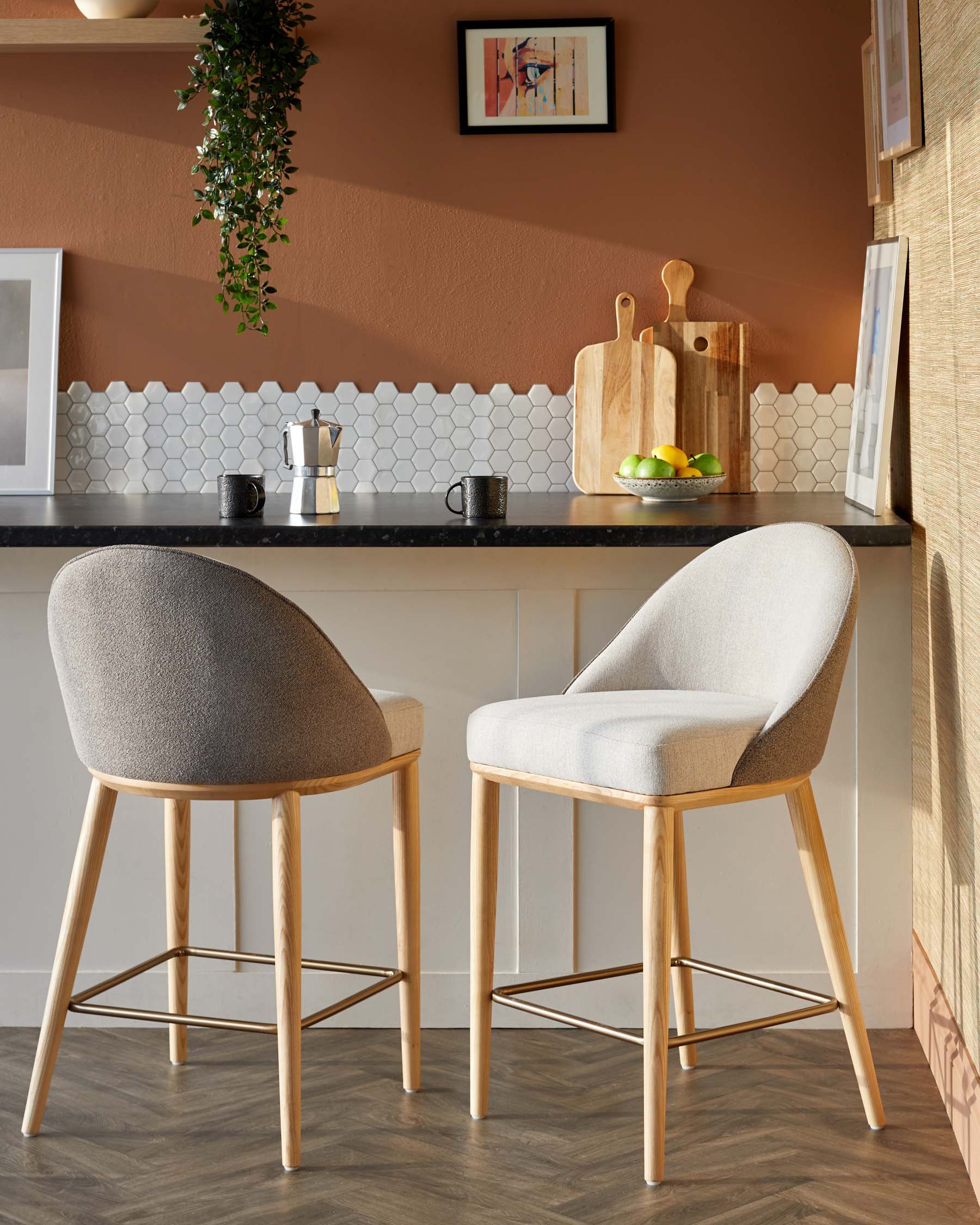 Two stylish bar stools with wooden legs and upholstered seats, set against a warm-colored wall and modern kitchen backdrop.