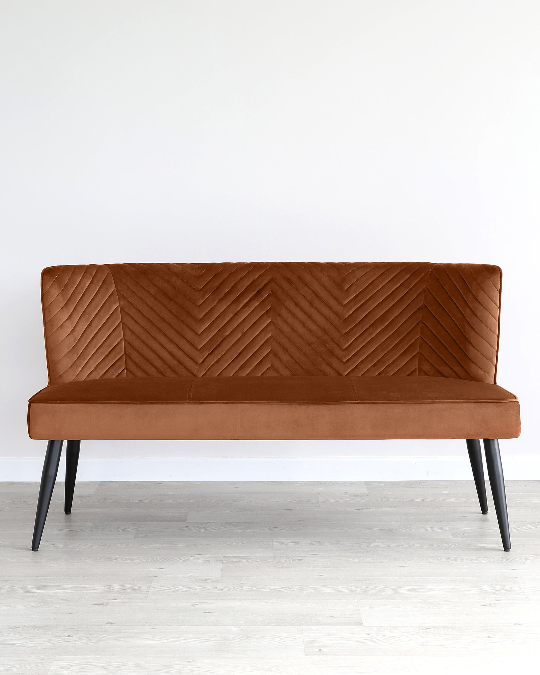 Modern chestnut brown upholstered bench with a chevron pattern on the backrest, simplified straight lines, and angled black metal legs, against a white wall on a light wooden floor.