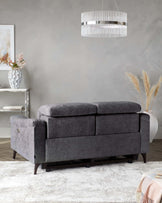 A modern grey upholstered sofa with plush cushions, paired with a stylish pendant light and decorative vase on a side table.