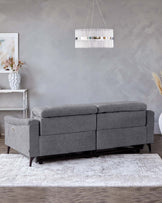 A modern gray sofa with plush cushions, paired with a chic chandelier and a sleek side table, set on a decorative rug.