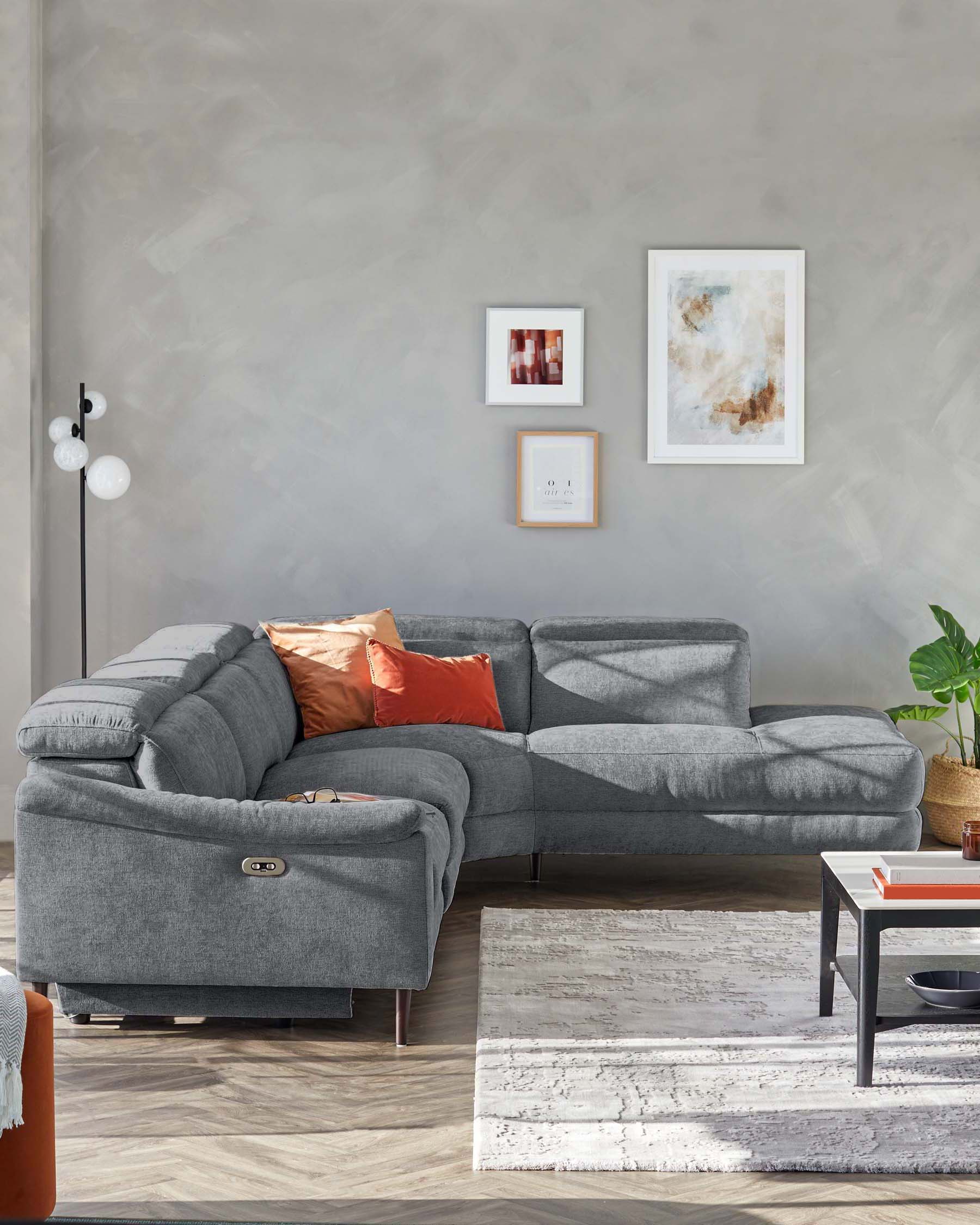 Gray sectional sofa with orange accents, accompanied by a coffee table and a textured rug, set against a light wall.