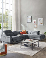 A modern gray sectional sofa with plush cushions, an orange accent pillow, and a sleek coffee table on a textured rug.