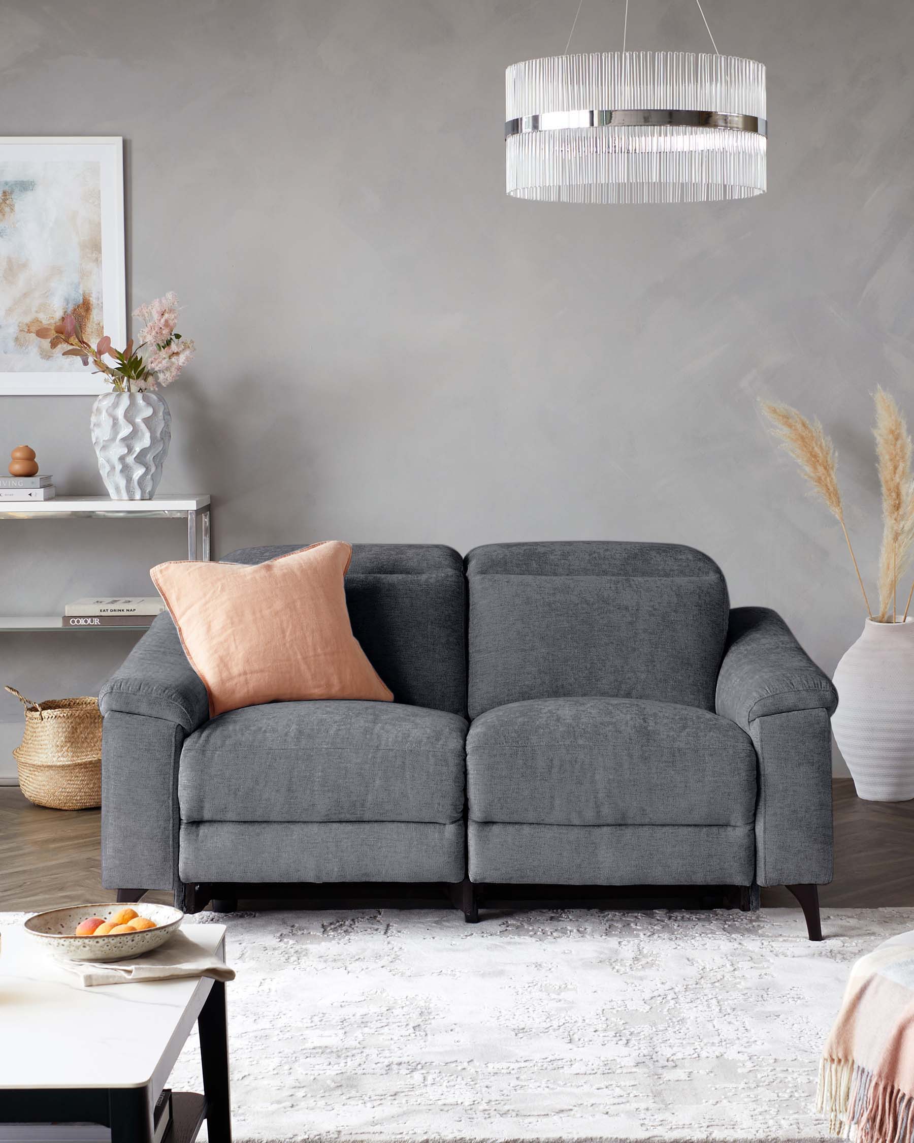 A cozy gray loveseat with a decorative pillow, set against a neutral wall, alongside a coffee table and stylish decor.