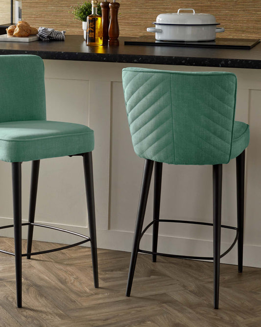 Two stylish bar stools with a mint green fabric seat and quilted backrest, supported by sleek black metal legs.