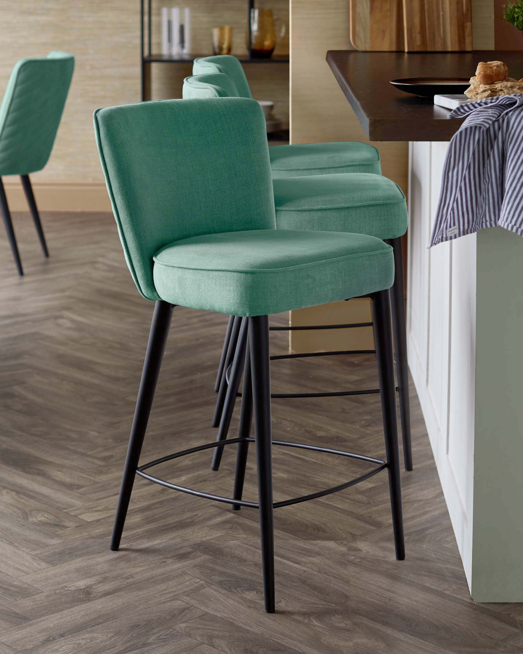 A set of modern turquoise barstools with sleek black legs, complementing a stylish kitchen counter.