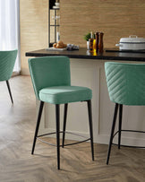 Two modern mint green barstools with black legs, complemented by a stylish counter with kitchen essentials and decor.