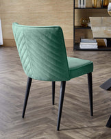 Elegant green upholstered chair with a quilted back, featuring sleek black legs, perfect for modern dining spaces.