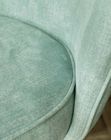 Close-up of a soft, mint-green upholstered chair with gentle curves and a smooth texture, perfect for modern interiors.