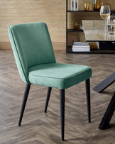 A modern green upholstered dining chair with sleek black legs, complementing a stylish dining space.