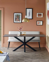 A sleek black table with an X-frame base paired with a modern gray bench, accented by a stylish pendant light and decor.