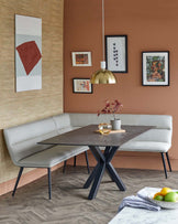 A modern dining setup featuring a dark table, gray upholstered bench, and a sleek gold pendant lamp.