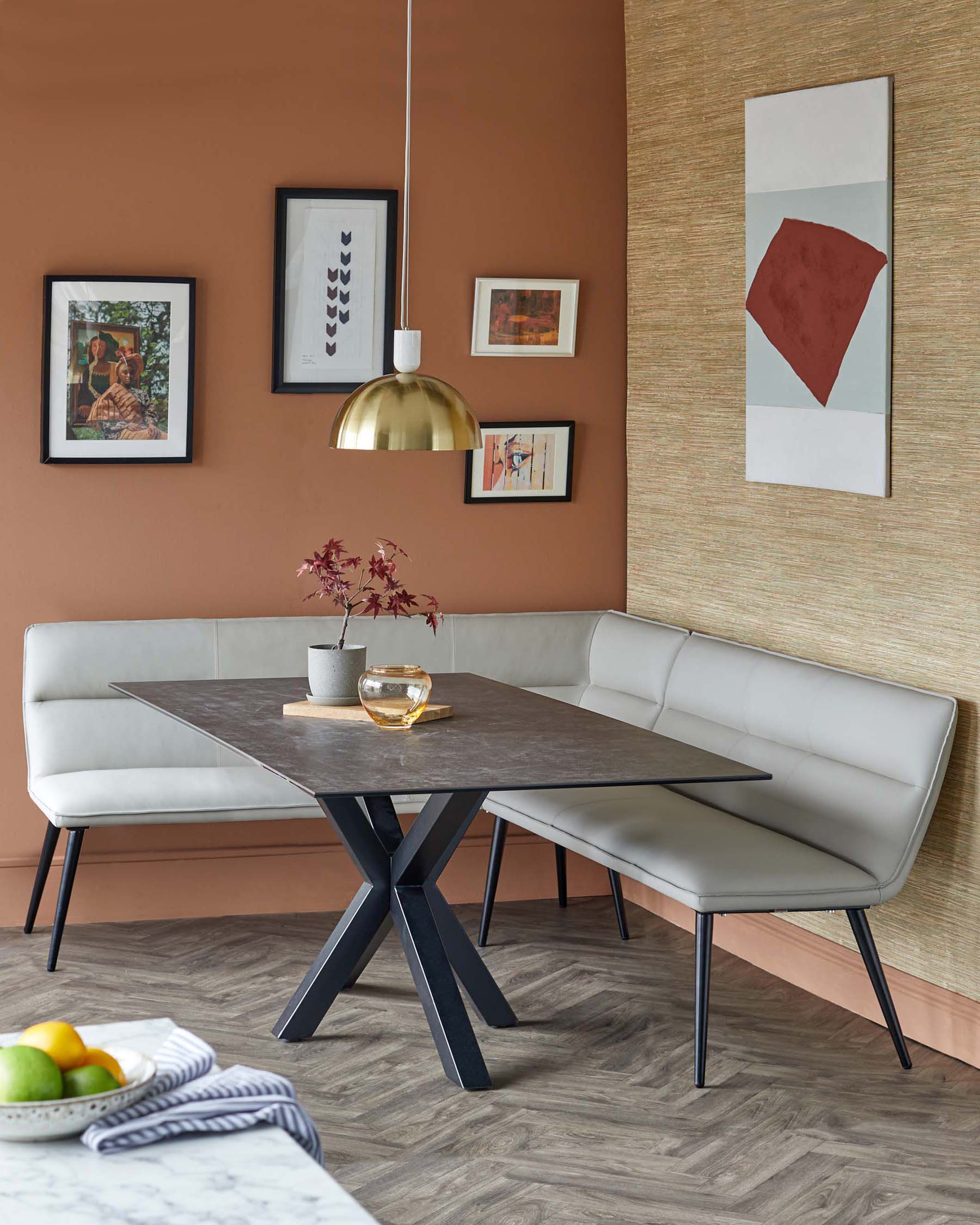 Modern dining set featuring a sleek black table with an angular base and light grey upholstered benches in a cozy nook.