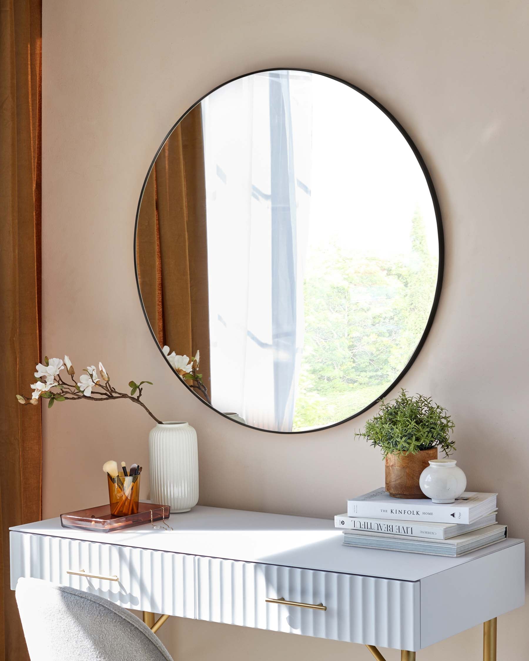 Elegant white fluted-front console table with brass handles, positioned against a pale wall under a large circular mirror.