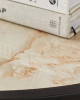 The image is not displaying any furniture. It shows a close-up of a stack of books with indistinct titles on a marbled surface, possibly a tabletop, with a blurred background.