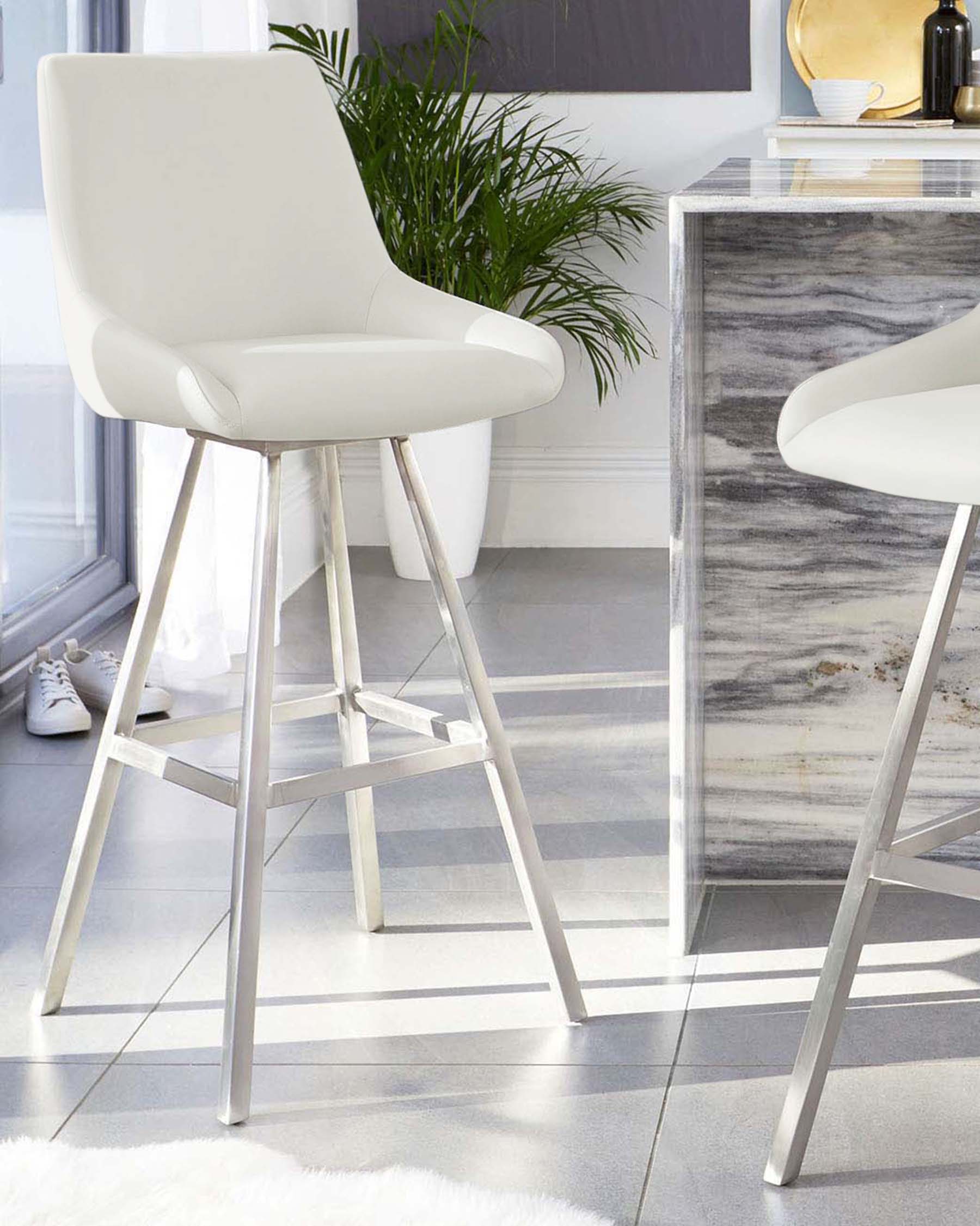 Modern white bar stools with sleek metal legs, featuring ergonomic backs, complement a stylish kitchen setting.