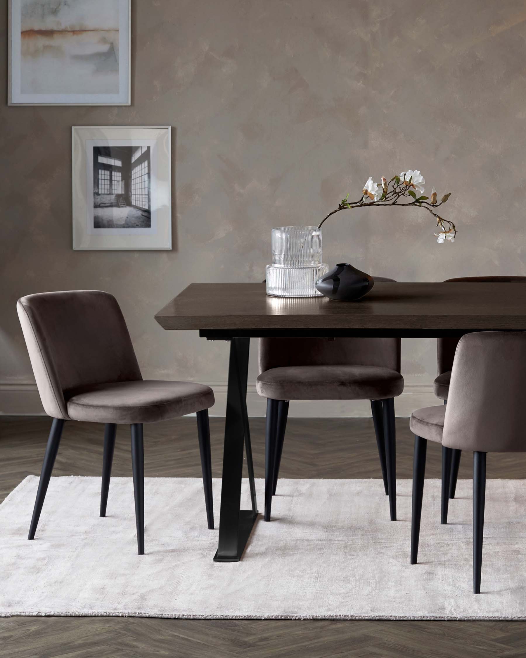 Elegant dining table with sleek black legs, complemented by plush grey chairs on a soft white rug, set against a neutral wall.