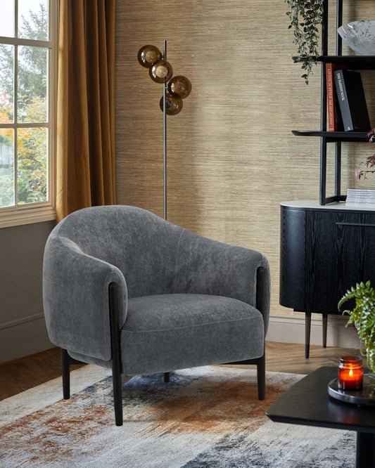 A chic gray upholstered armchair with tapered black legs, paired with a sleek floor lamp and a modern black side table.