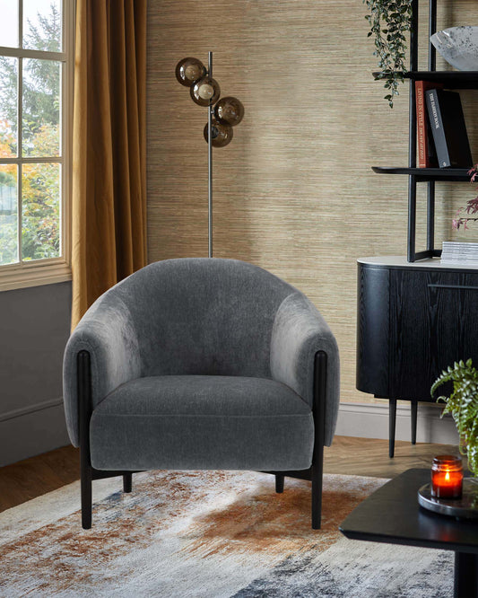 A stylish gray upholstered chair with rounded edges, paired with a modern floor lamp and black furniture accents.