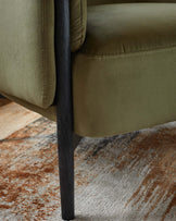 Sleek olive green upholstered chair with a modern design, featuring black wooden legs and a minimalistic style.