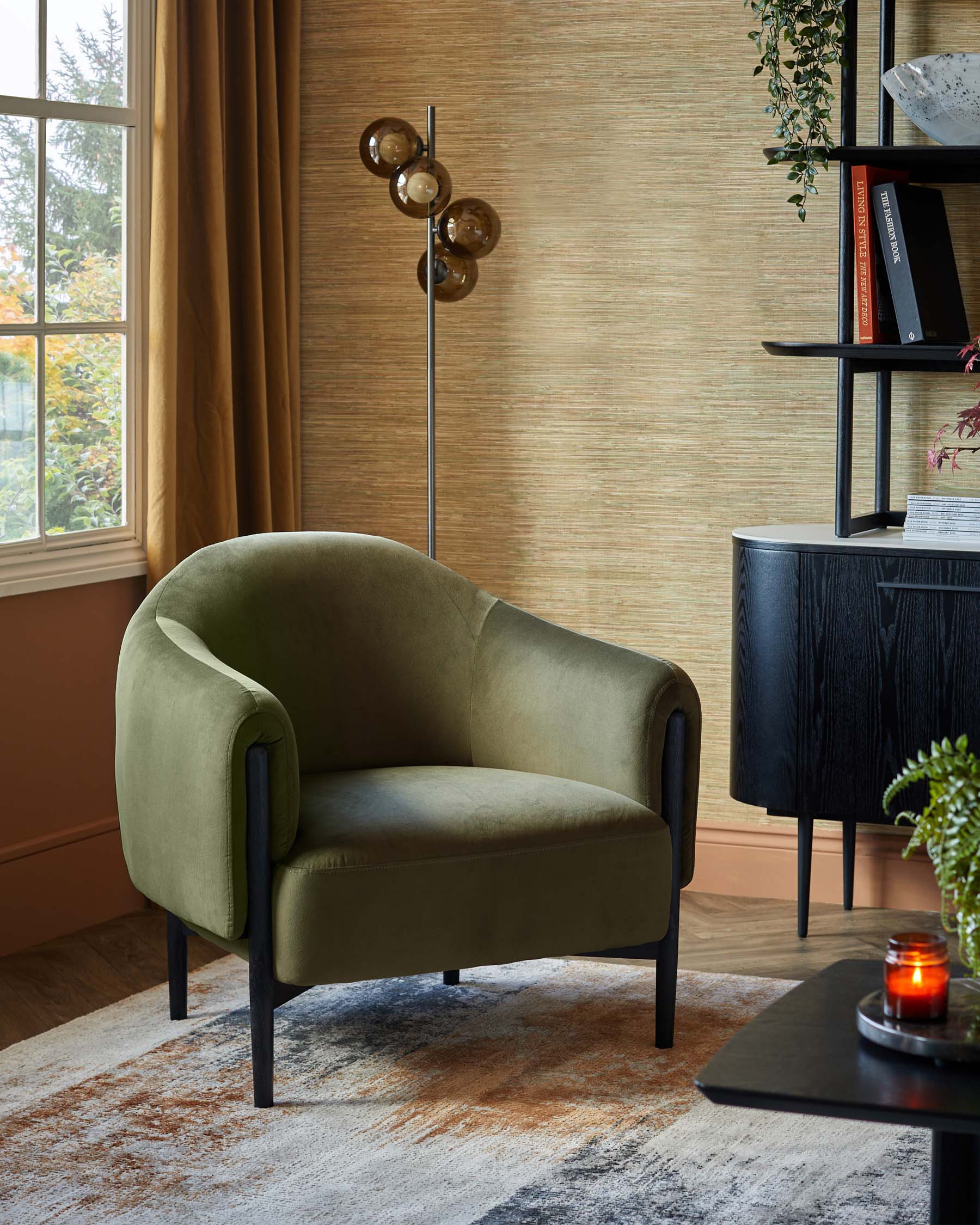 A curved green armchair, modern floor lamp with round glass bulbs, sleek black shelving, and a cozy area rug.