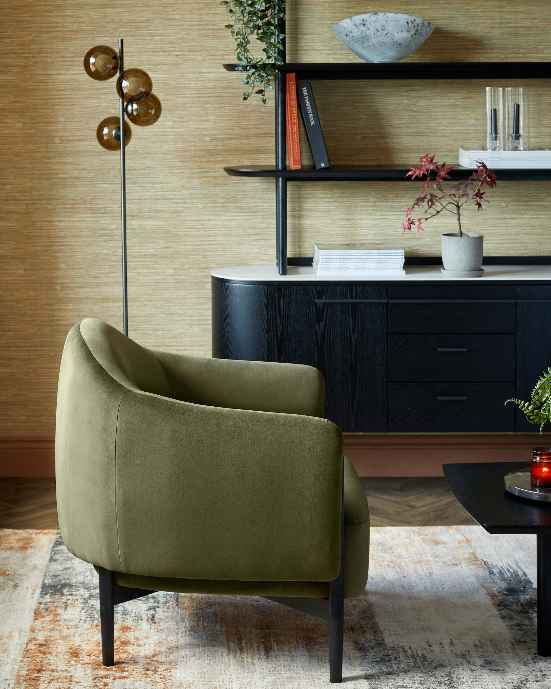 A green upholstered chair, curved and modern, beside a sleek black console, decorative shelves, and a stylish floor lamp.